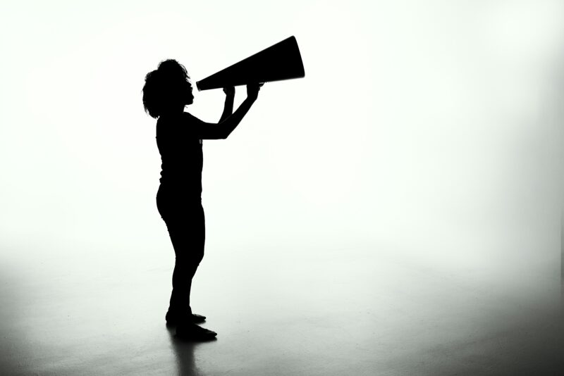 Silhouette of a woman holding an analog megaphone.