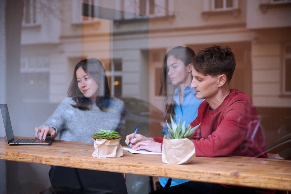 Sovereign tech Agency team sitting and working together, photographed through a window