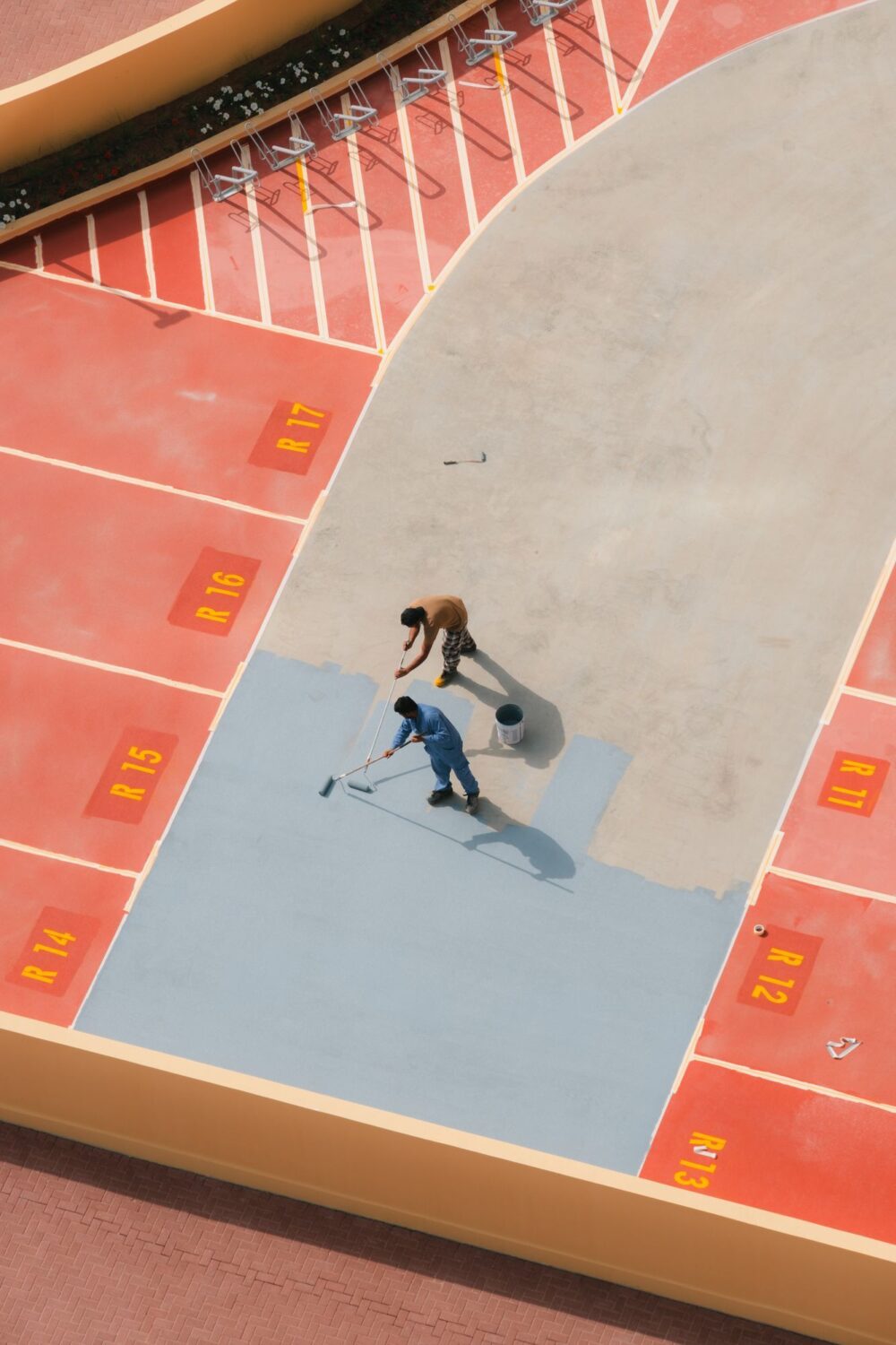 Two People Are Painting The Concrete Between The Lanes